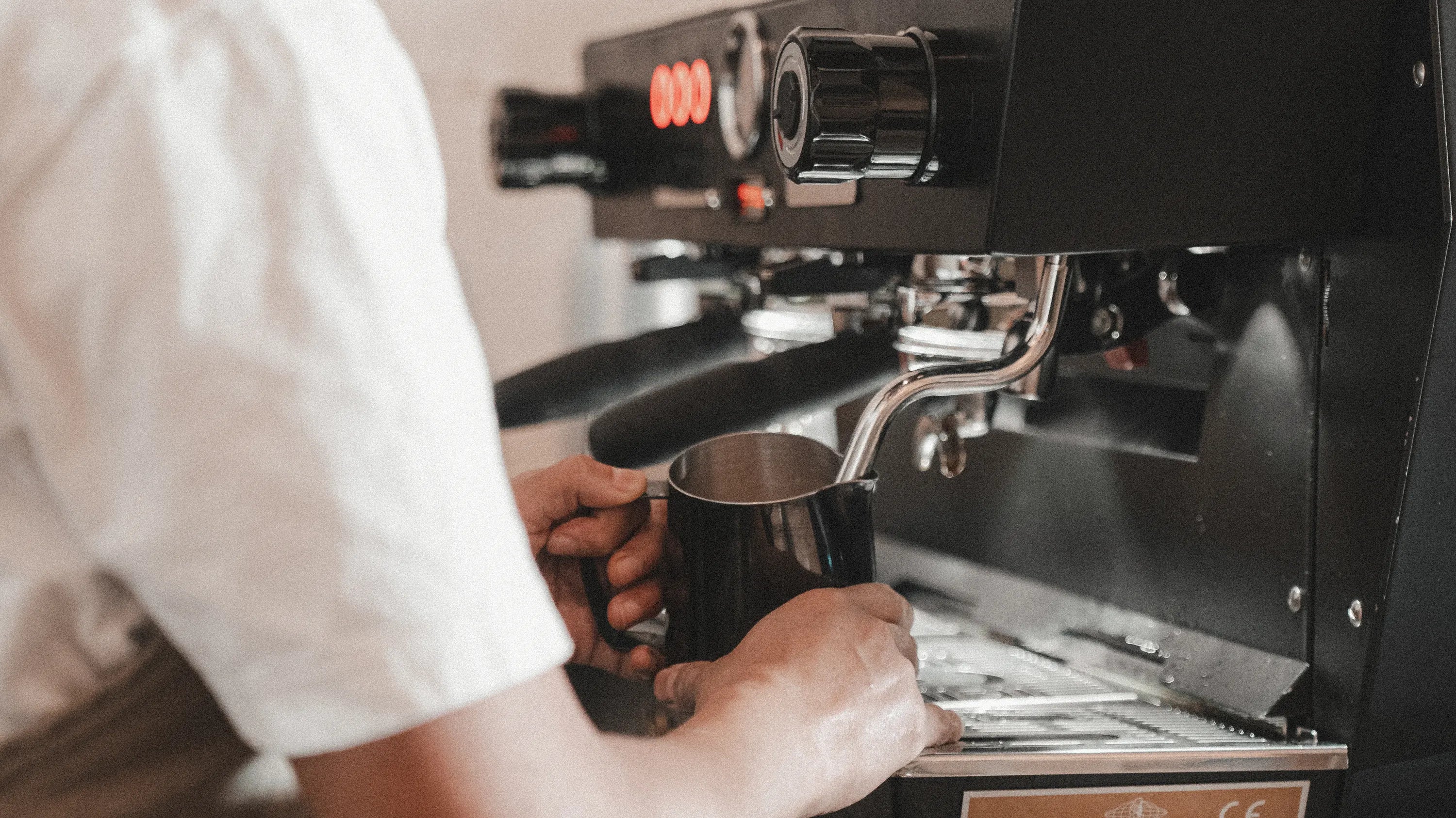 A barista in the cafe frothing milk with la marzocco kb90