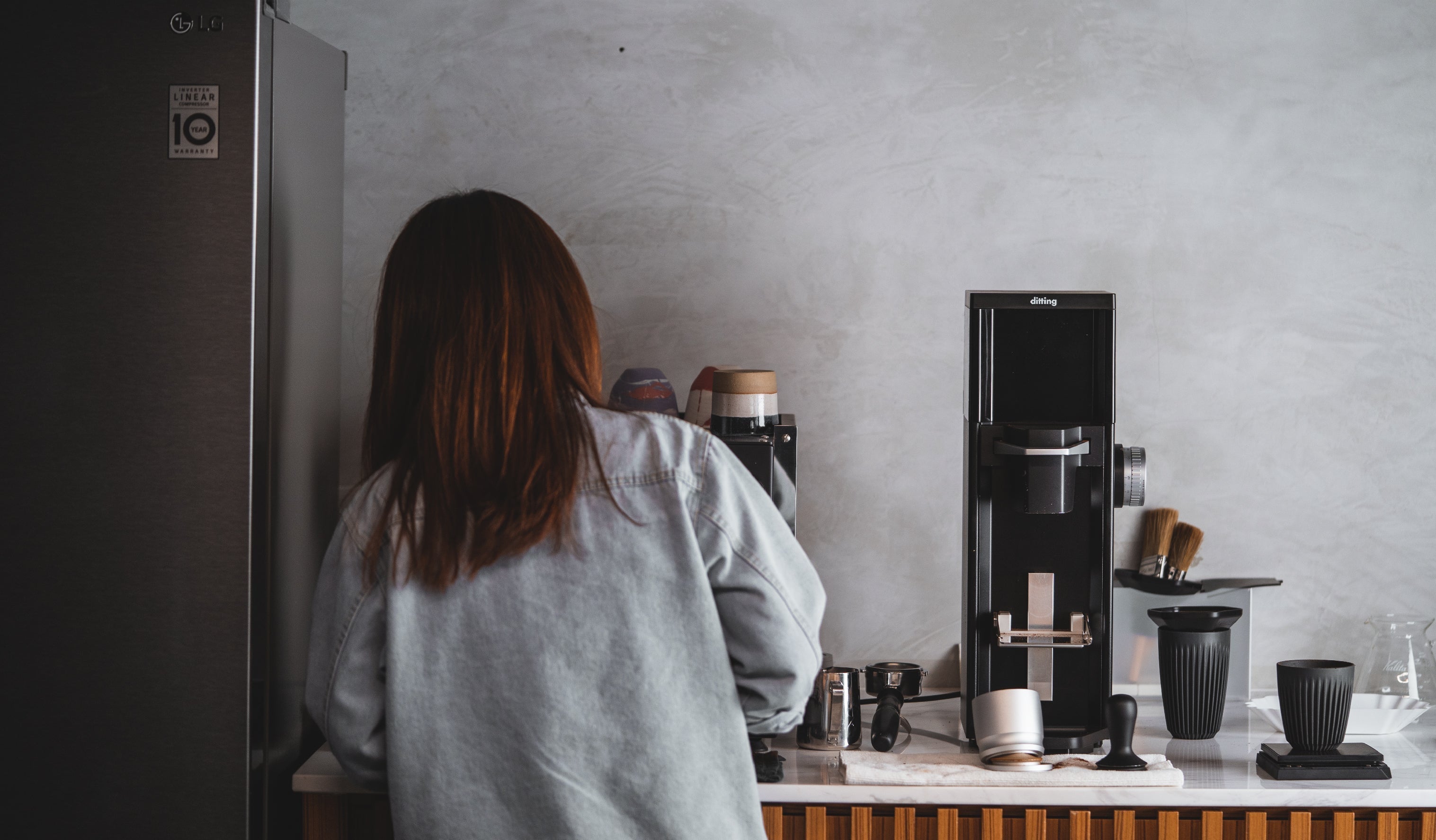 A woman stands in front of a coffee maker, poised to brew coffee, highlighting a charming and functional kitchen environment.